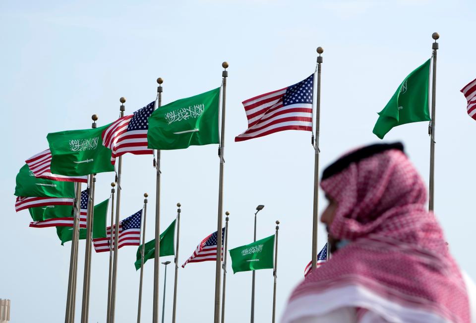 A man stands under American and Saudi Arabian flags prior to a visit by US president Joe Biden, at a square in Jeddah, Saudi Arabia, Thursday, 14 July 2022 (AP)