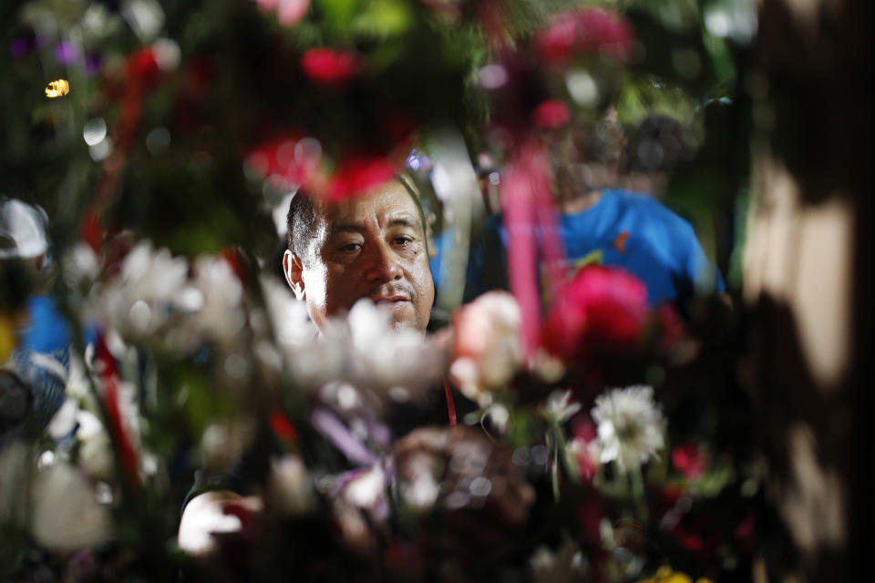 Gregorio De la Rosa places a flower on a wall during a ceremony to dedicate a memorial garden for victims, Monday, Oct. 1, 2018, on the anniversary of the mass shooting a year earlier, in Las Vegas. De la Rosa's stepson Erick Silva was killed in the shooting. (AP Photo/John Locher)