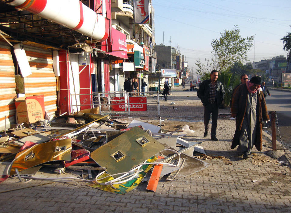 Civilians walk past damages at the site of a car bomb attack near the al-Farasha pastry shop in the southeastern district of New Baghdad, Iraq, Thursday, Jan. 30, 2014. Car bombs and a shooting, mainly in Shiite areas, killed and wounded scores of people in the Iraqi capital on Wednesday, officials said, as authorities released a rare photograph of a man they say is the leader of al-Qaida's local branch. Since late December, members of Iraq's al-Qaida branch have taken over parts of Ramadi, capital of the largely Sunni province of Anbar. They also control the center of the nearby city of Fallujah. Government forces and allied tribes have been trying to wrest control back from the militants. (AP Photo/Khalid Mohammed)