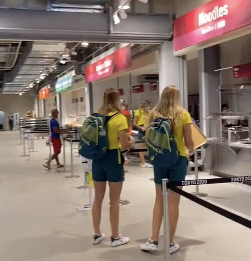 Two Team Australia members stand while waiting for their food