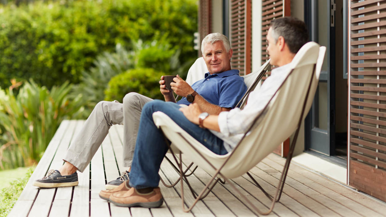 Full length of mature male friends spending leisure time at yard.