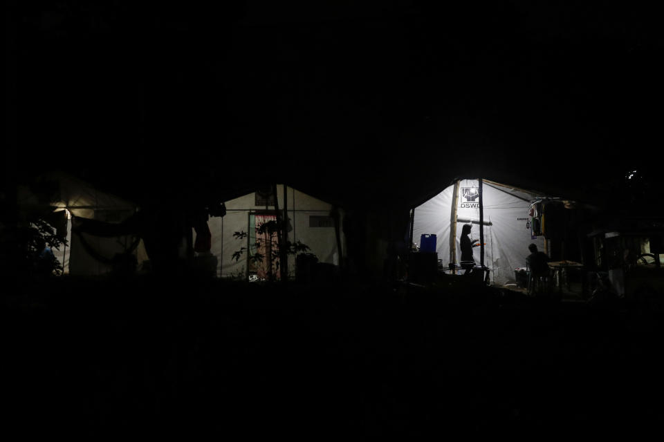 Residents who used to live at Taal volcano stand outside their tents at a relocation site in Balete, Batangas province, Philippines, Sunday, Jan. 10, 2021. Some families are still living in tents and have resorted to taking odd jobs to make a living as the government has prevented them from returning back to their homes almost a year after Taal volcano erupted on Jan. 12, 2020. The eruption displaced thousands of villagers living near the area and delivered an early crisis this year for one of the world's most disaster-prone nations a couple of months before the COVID-19 pandemic broke in the country. (AP Photo/Aaron Favila)