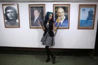 Bexy Estopina, 21, poses for a photographer (not pictured) in front of pictures of Cuba's former President Fidel Castro (R), Cuba's President Raul Castro (C) and late Cuban revolutionary hero Ernesto "Che" Guevara during the Cuban Otaku festival at a cinema in Havana, Cuba, July 24, 2016. REUTERS/Alexandre Meneghini