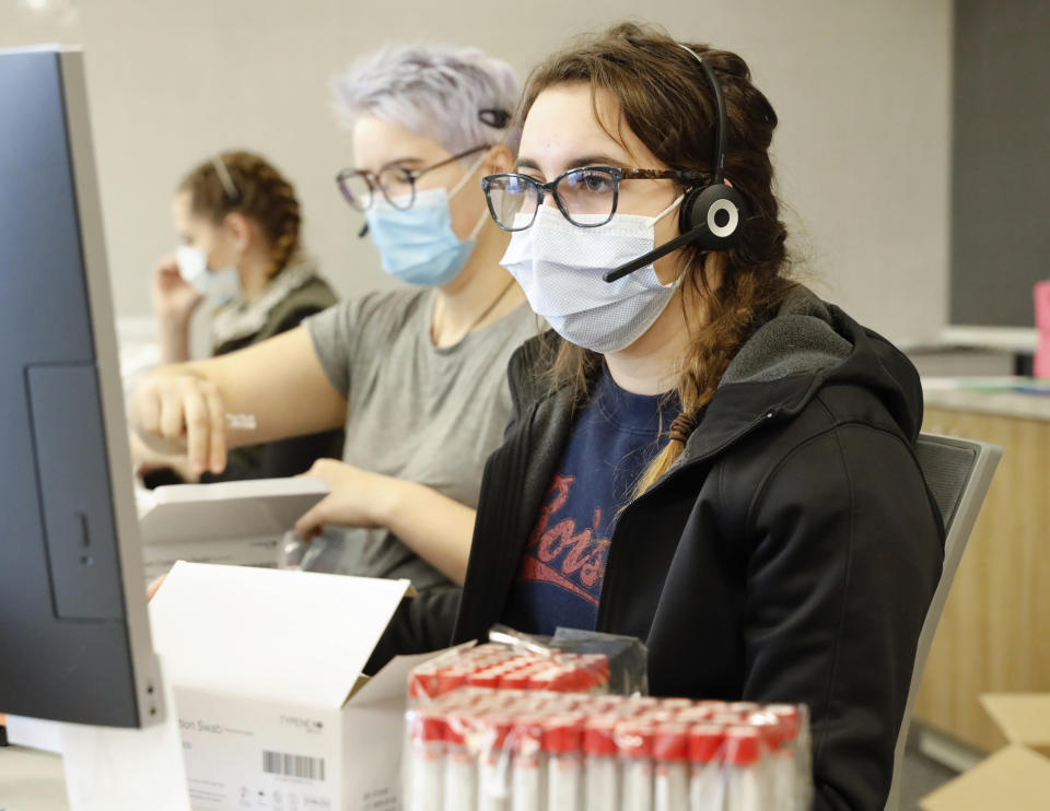 Employees schedule COVID-19 tests and prepare test kits at Primary Health Medical Group's clinic in Boise, Idaho, on Tuesday, Nov. 24, 2020. Troops direct people outside the urgent-care clinic revamped into a facility for coronavirus patients as infections and deaths surge in Idaho and nationwide. (AP Photo/Otto Kitsinger)