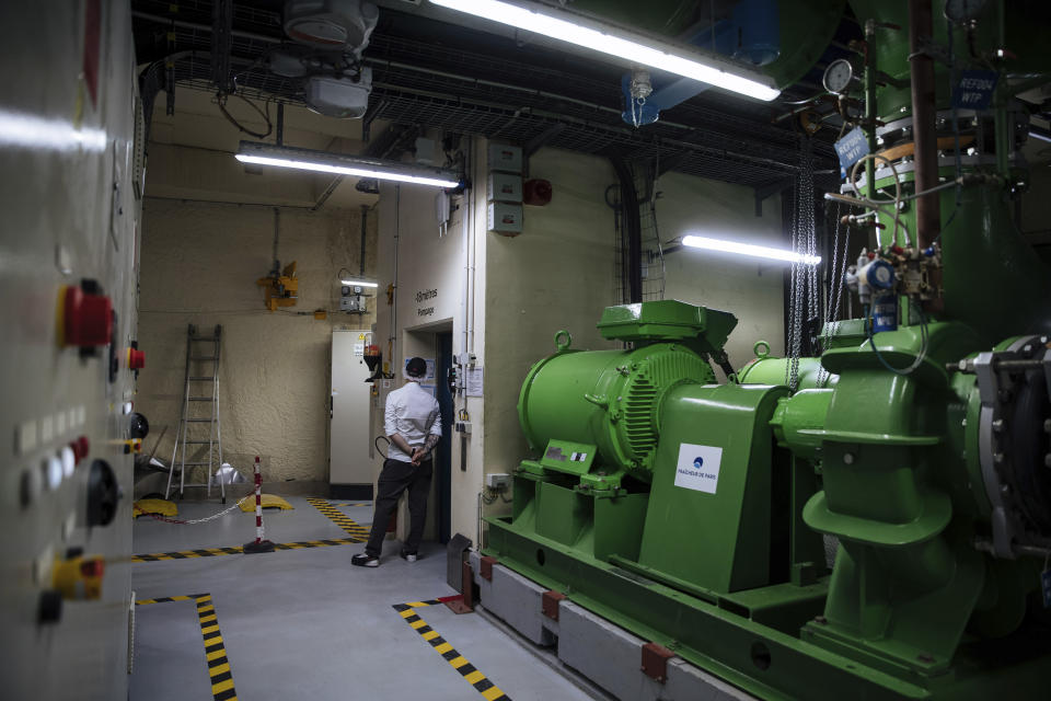 A worker waits near an elevator at part of Fraicheur de Paris' underground cooling system on Tuesday, July 26, 2022, in Paris. Paris City Hall has signed an ambitious contract to triple the size of the network which would make it the largest urban cooling system in the world. (AP Photo/Lewis Joly)