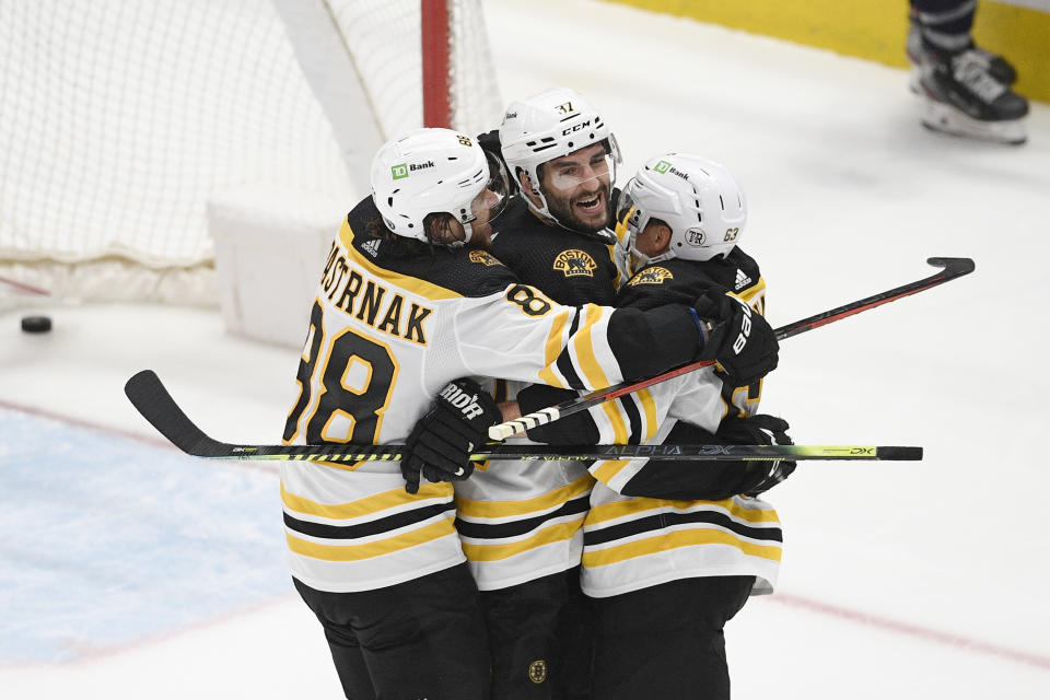 FILE - Boston Bruins center Patrice Bergeron (37) celebrates his goal with right wing David Pastrnak (88) and left wing Brad Marchand (63) during the third period in Game 5 of an NHL hockey Stanley Cup first-round playoff series against the Washington Capitals, Sunday, May 23, 2021, in Washington. Bruins captain Patrice Bergeron is coming back for another season. Almost three months after he left the ice without any certainty that he would return, the five-time Selke Trophy winner signed a one-year deal with the Bruins on Monday, Aug. 8, 2022. (AP Photo/Nick Wass, File)