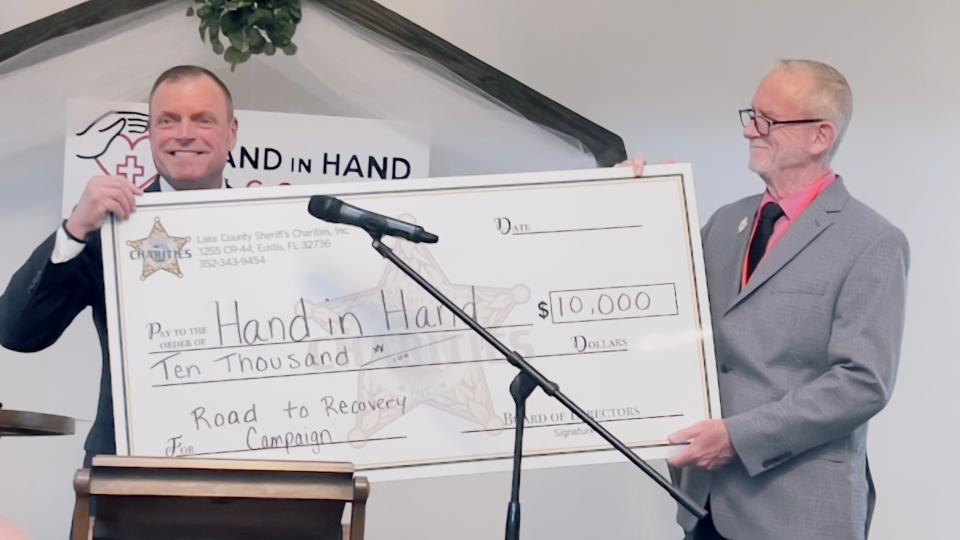 Sheriff Peyton Grinnell presents a check of $10,000 from the Lake County Sheriff's Office to David Douglas, director of Hand in Hand Recovery.