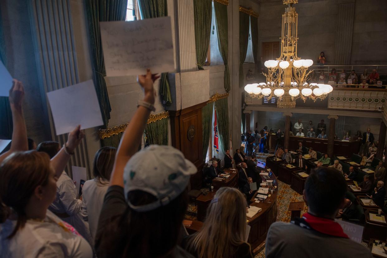 People hold signs while the Senate holds session at the State Capitol Building on Thursday, Aug. 24, 2023, in Nashville, Tenn.