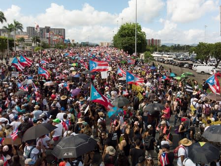 People gather along a main highway during a protest calling for the resignation of Governor Ricardo Rossello in San Juan