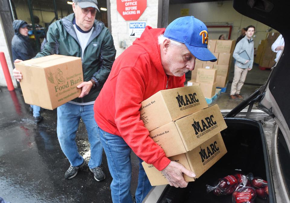 Volunteers Dan Bortner, 71, back left, and Jerry Kardos, 73, help load food items into a car during Second Harvest Food Bank's Poverty Express food pick-up in Erie on Jan. 4, 2023.