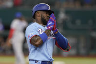 Texas Rangers' Adolis Garcia gestures as he rounds the bases after hitting a two-run home run that also scored teammate Nathaniel Lowe during the third inning of a baseball game against the Toronto Blue Jays in Arlington, Texas, Sunday, Sept. 11, 2022. (AP Photo/LM Otero)