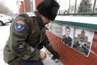 A Russian Cossack lights a candle near a photo of Russian police senior sergeant Dmitry Makovkin, who was killed in a suicide bomb blast at the city's main railway station, in front of the Kazan Orthodox Cathedral in the southern Russian city of Volgograd, January 4, 2014. REUTERS/Vasily Fedosenko