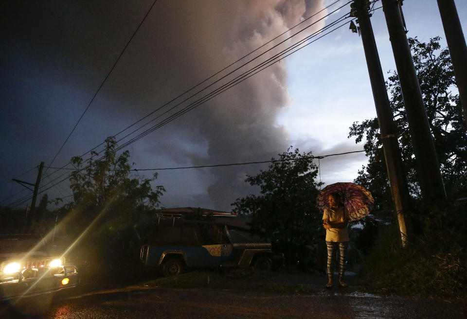 A resident prepares to evacuate as Taal Volcano erupts, Sunday Jan. 12, 2020, in Tagaytay, Cavite province, outside Manila, Philippines. A tiny volcano near the Philippine capital that draws many tourists for its picturesque setting in a lake belched steam, ash and rocks in a huge plume Sunday, prompting thousands of residents to flee and officials to temporarily suspend flights. (AP Photo/Aaron Favila)