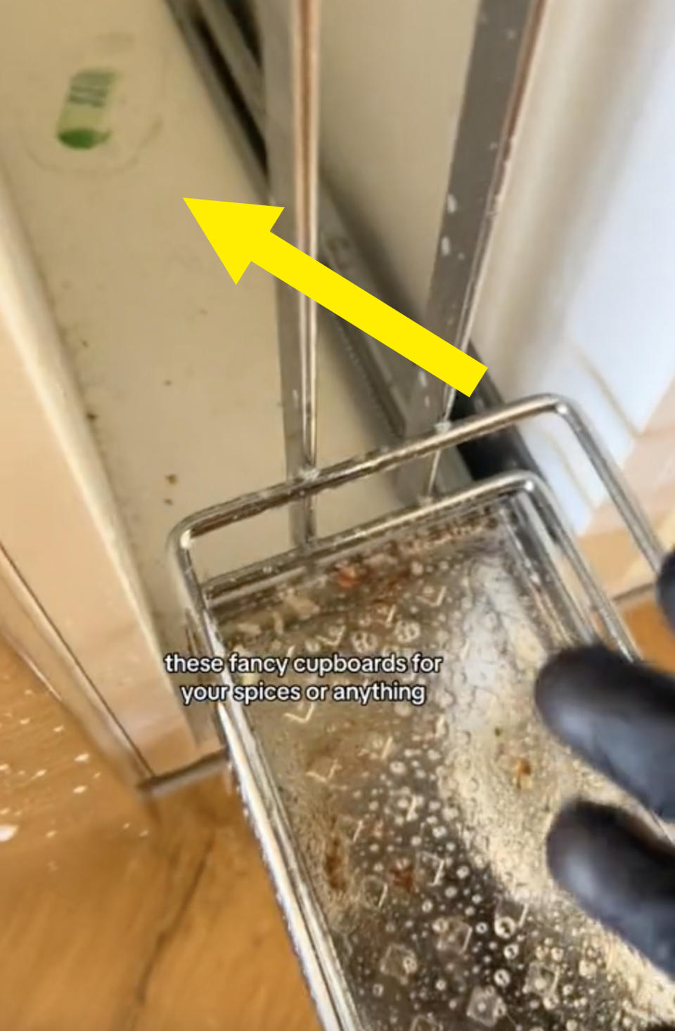 a roll out spice rack drawer with crumbs and debris left in the inside