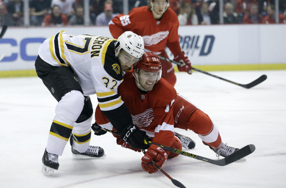 Boston Bruins center Patrice Bergeron (37) and Detroit Red Wings center Riley Sheahan (15) battle for the puck during the first period of Game 3 of a first-round NHL hockey playoff series in Detroit, Tuesday, April 22, 2014. (AP Photo/Carlos Osorio)