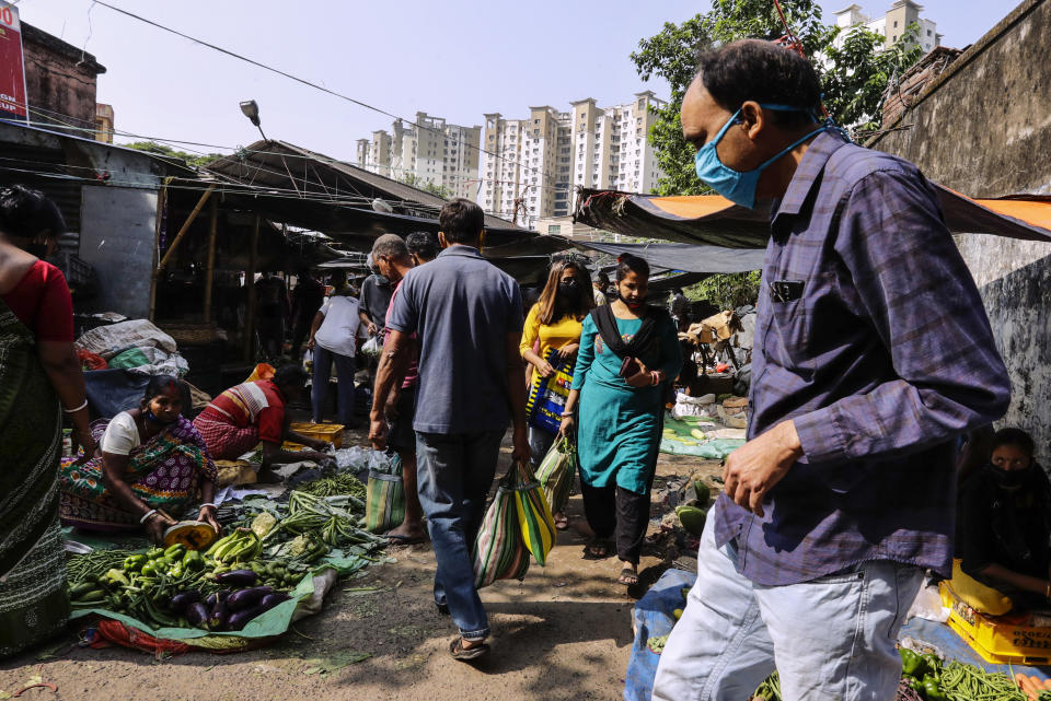 People wearing face mask as a precautionary measure against the coronavirus buy vegetables inside a narrow alley in Kolkata, India, Sunday, Nov. 22, 2020. (AP Photo/Bikas Das)