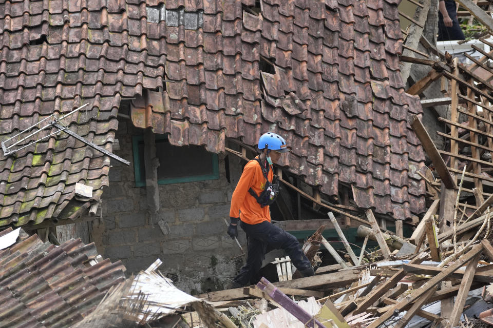A rescuer walks amid rubble during the search for victims at a village hit by an earthquake-triggered landslide in Cianjur, West Java, Indonesia, Thursday, Nov. 24, 2022. On the fourth day of an increasingly urgent search, Indonesian rescuers narrowed their work Thursday to the landslide where dozens are believed trapped after an earthquake that killed hundreds of people, many of them children. (AP Photo/Tatan Syuflana)
