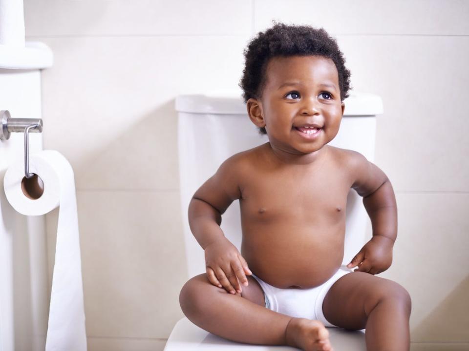 A baby sits on the toilet.