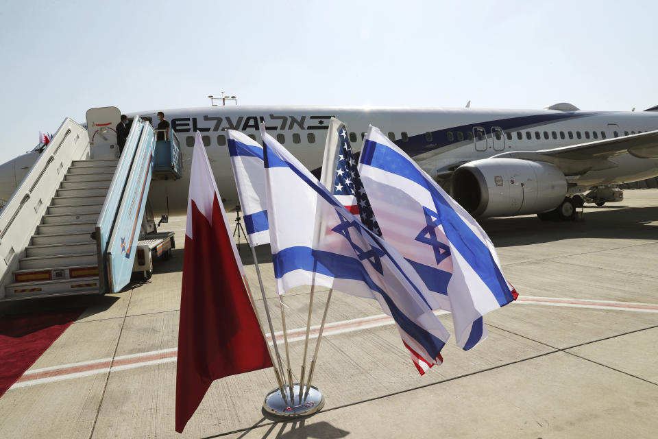 Banderas de Israel, Bahrein y Estados Unidos ondean cerca de un avión israelí que iba a despegar hacia Bahrein el 18 de octubre de 2020, en el Aeropuerto Internacional Ben Gurión en Lod, Israel. (Ronen Zvulun/Pool foto vía AP)