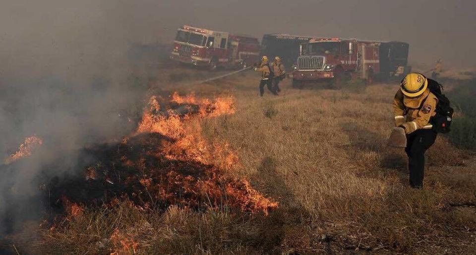 Personal de Cal Fire SCU trabaja para cortar el paso a las llamas en la mediana de la Interstate 580 al sur de Tracy durante el Corral Fire, el sábado. El incendio forestal de más de 12,000 acres quemó varias estructuras y cerró una autopista interestatal al suroeste de Tracy. Siguen vigentes las órdenes de evacuación.