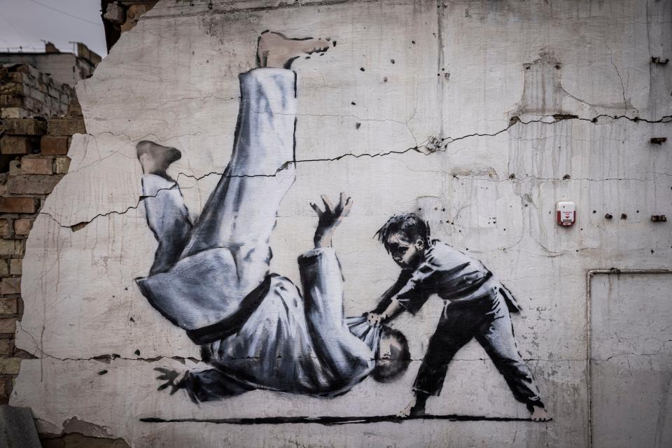 Graffiti of a child throwing a man on the floor in judo clothing is seen on a wall amid damaged buildings in Borodyanka on November 11, 2022 in Kyiv Region, Ukraine. The art work has sparked online speculation over whether the graffiti artist Banksy has been working in Ukraine.