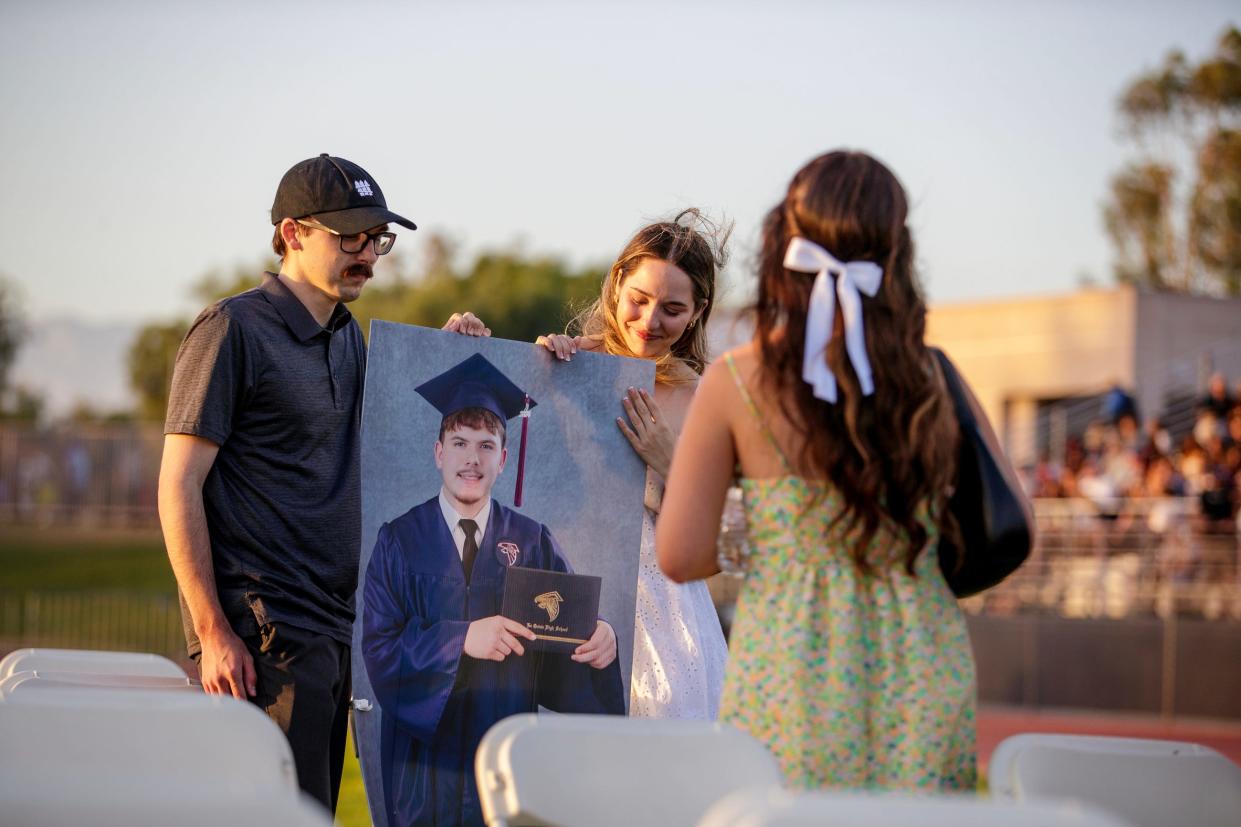 Before the start of the commencement Thursday at La Quinta High School, Darian Ramos, left, and Jenna Ramos spend a moment where their brother, Jaden Ramos, would have been seated. On Sunday, May 19, Jaden Ramos was shot and killed at a post-prom party.