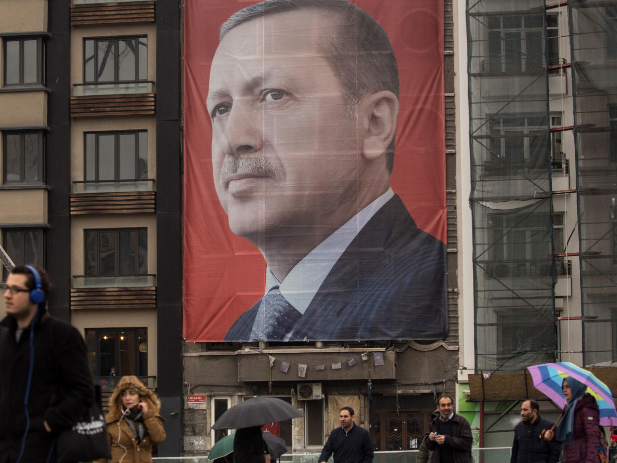 People walk past a large banner showing the portrait of Turkish President Recep Tayyip Erdogan in Taksim Square: Getty