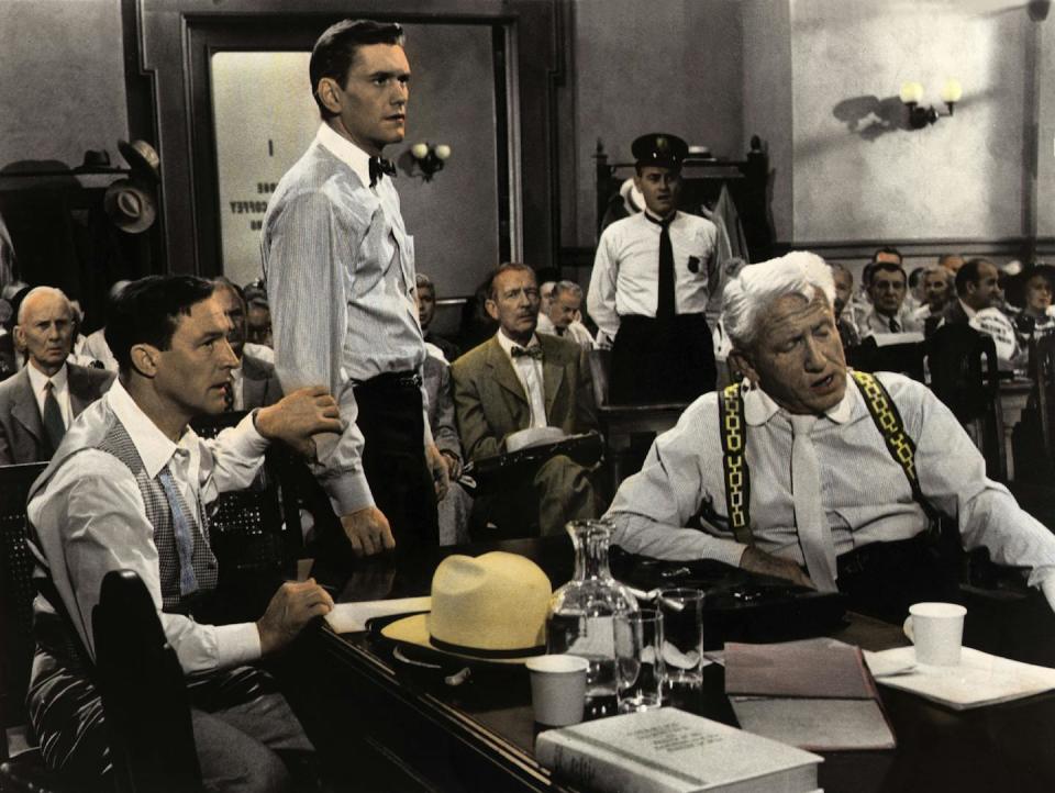 A lawyer and his plaintiff sit at a table in a crowded courtroom.