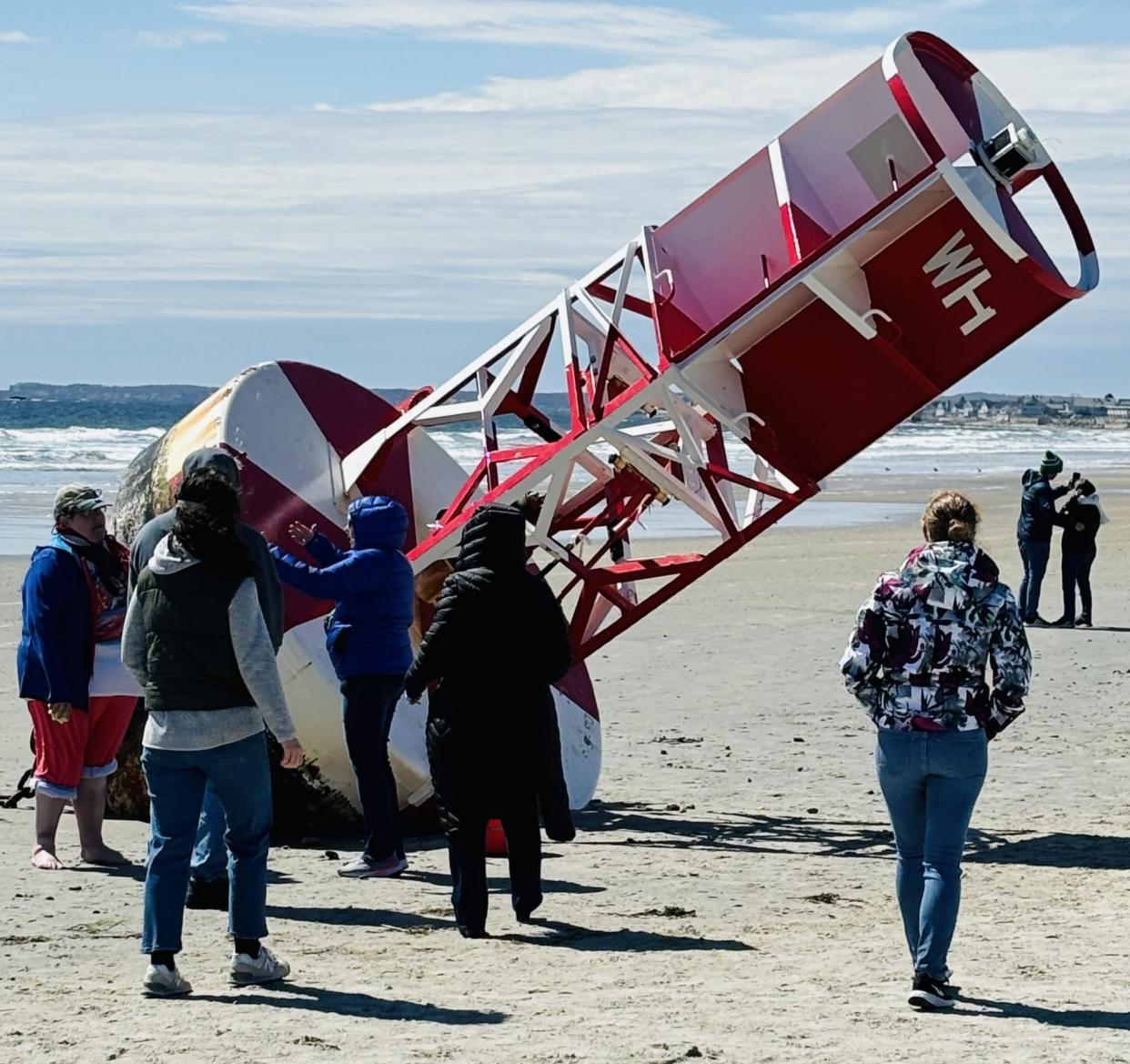 A crowd gathers around the buoy that washed up on Wells Beach in Maine, following a storm in early April 2024.