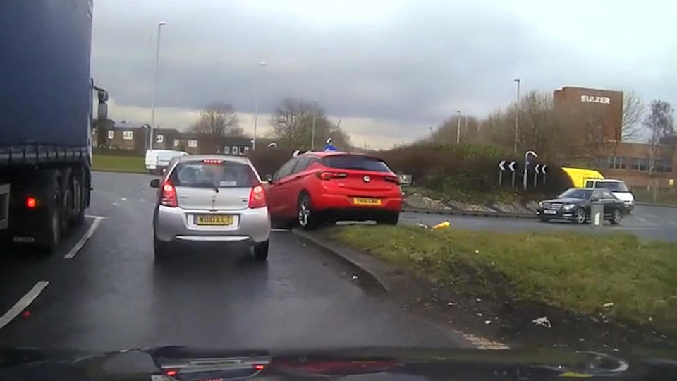 The police dashcam caught the moment the driver drove up on a verge next to a roundabout (SWNS)