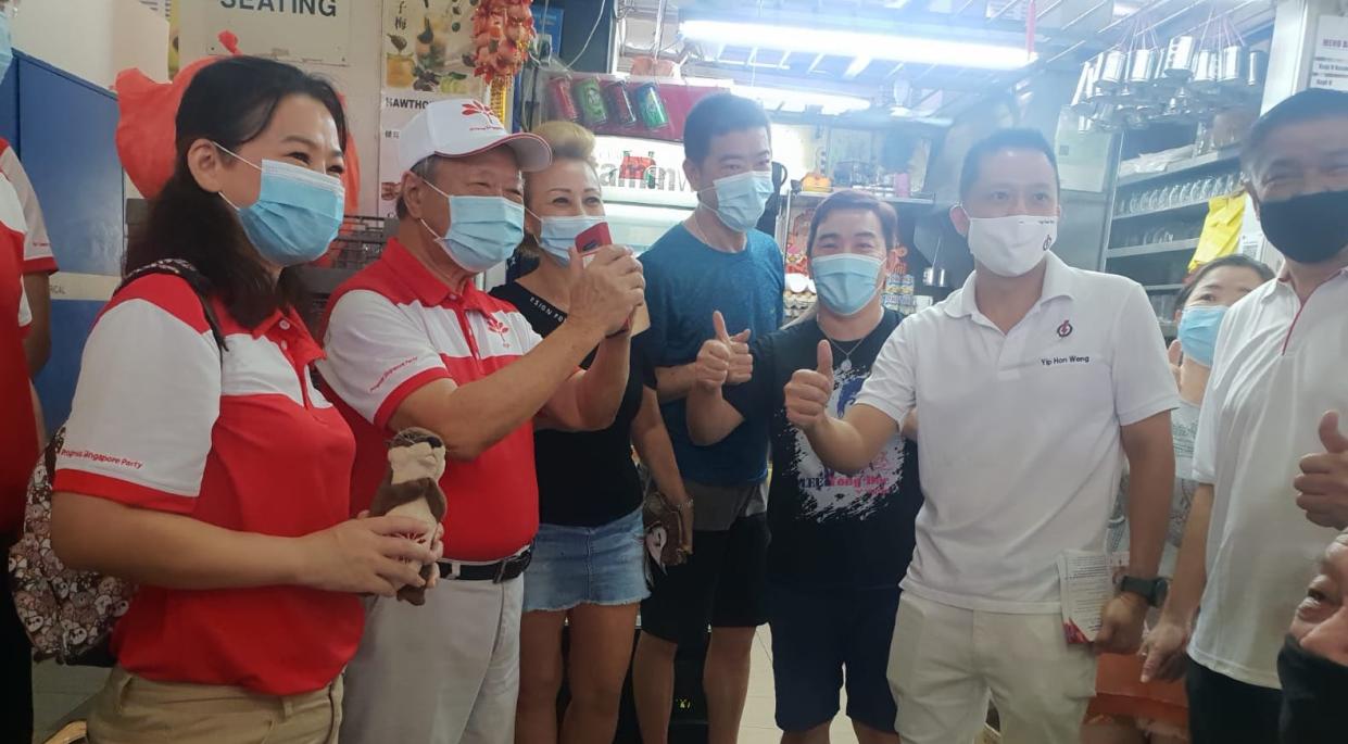 Progress Singapore Party secretary-general Tan Cheng Bock (second from left) with Yio Chu Kang SMC candidates Kayla Low (left) and People's Action Party's Yip Hon Weng (second from right) as well as market stallholders during a walkabout at Ang Mo Kio 628 Market. (PHOTO: Wan Ting Koh/Yahoo News Singapore)