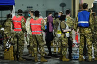 People flown out of Afghanistan leave a transport bus at Ramstein Air Base and are met by soldiers and helpers, in Ramstein-Miesenbach, Germany, Friday, Aug. 20, 2021. (Uwe Anspach/dpa via AP)