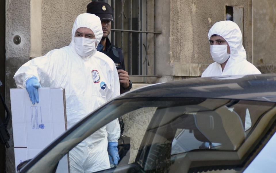  Policemen carry evidence during a search at the residence of a suspect - Credit: Atienza/EFE