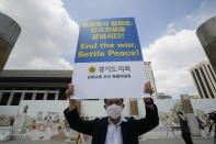 A man holds up a banner to demand the peace on the Korean peninsula near the U.S. Embassy in Seoul, South Korea, Tuesday, July 27, 2021. South Korea says the leaders of North and South Korea have agreed to restore suspended communication channels and improve ties. (AP Photo/Ahn Young-joon)