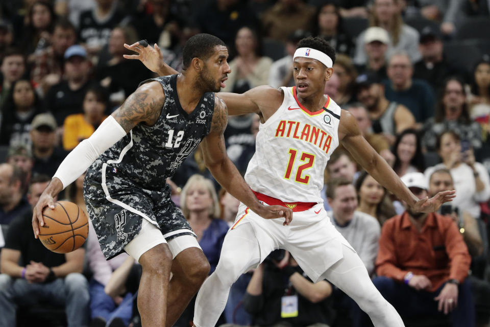 San Antonio Spurs center LaMarcus Aldridge, left, moves the ball past Atlanta Hawks guard Treveon Graham, right, during the first half of an NBA basketball game in San Antonio, Friday, Jan. 17, 2020. (AP Photo/Eric Gay)