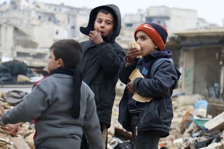 Boys eat bread as they wait to be evacuated from a rebel-held sector of eastern Aleppo, Syria December 16, 2016. REUTERS/Abdalrhman Ismail