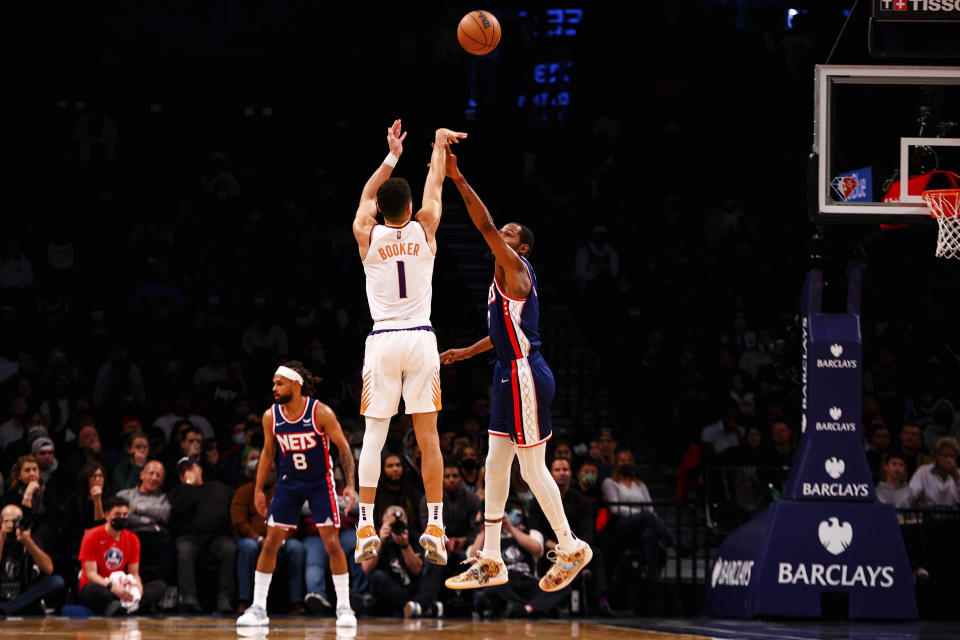 Phoenix Suns guard Devin Booker (1) shoots against Brooklyn Nets forward Kevin Durant (7) during the first half of an NBA basketball game, Saturday, Nov. 27, 2021, in New York. (AP Photo/Jessie Alcheh)