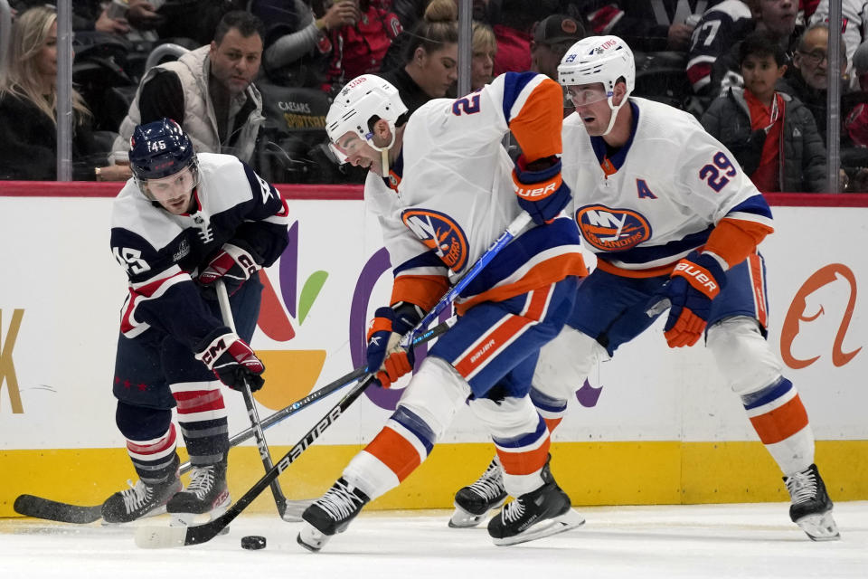 Washington Capitals center Matthew Phillips, left, New York Islanders center Kyle Palmieri, center, and Islanders center Brock Nelson, right, battle for control of the puck in the second period of an NHL hockey game, Thursday, Nov. 2, 2023, in Washington. (AP Photo/Mark Schiefelbein)