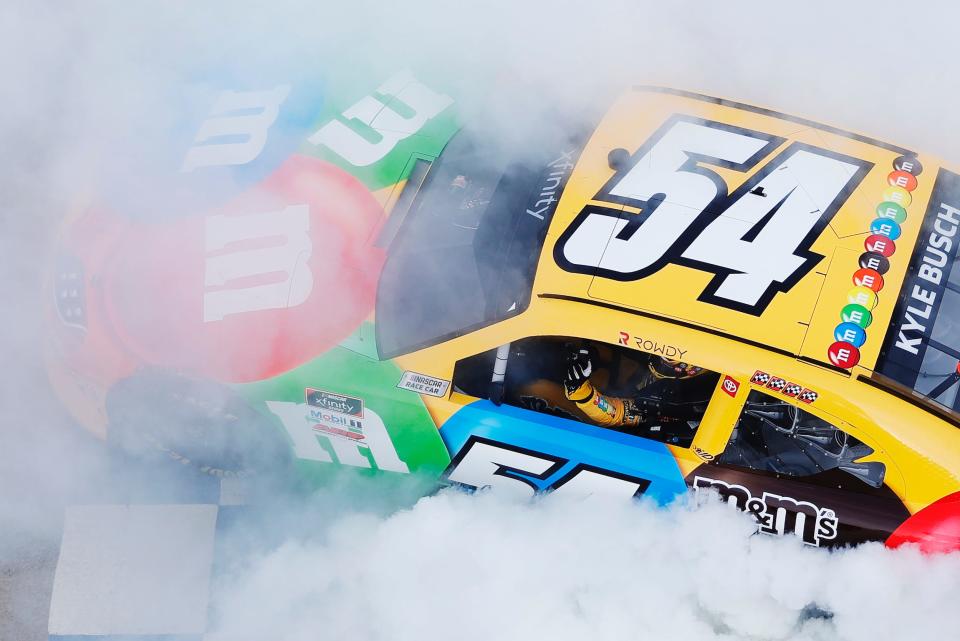 Kyle Busch, driver of the #54 M&M's Toyota, celebrates with a burnout after winning the NASCAR Xfinity Series Tennessee Lottery 250 at Nashville Superspeedway.