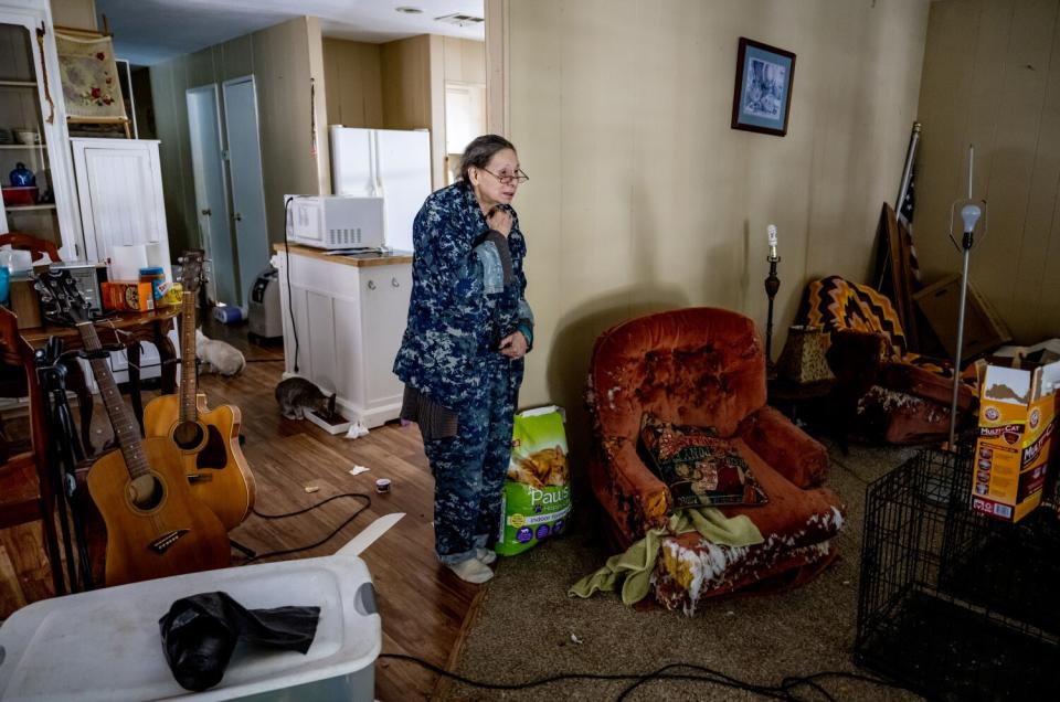 A woman stands in the living room of a small home.