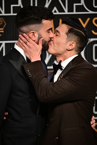 <p>FREDERIC J. BROWN/AFP via Getty</p> Joel Kim Booster kisses John Michael Kelly at the 2024 Emmys