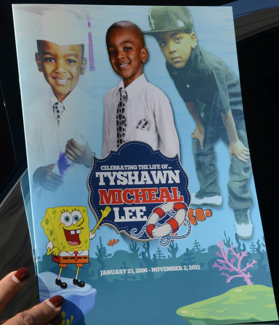 In this Tuesday, Nov. 10, 2015, file photo, a mourner holds the program for the funeral of 9-year-old Tyshawn Lee at St. Sabina Church in Chicago.