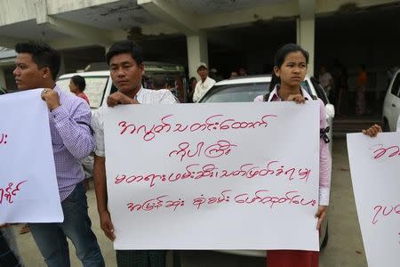 Supporters hold signs during a funeral ceremony for slain journalist Par Gyi at the Yaway cemetery in Yangon, November 7, 2014. The sign reads, "There needs to be an investigation into the death of the slain journalist Par Gyi." REUTERS/Soe Zeya Tun