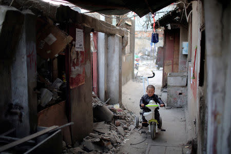 A boy rides a tricycle in between semi demolished houses in Guangfuli neighbourhood, in Shanghai, China, March 28, 2016. REUTERS/Aly Song
