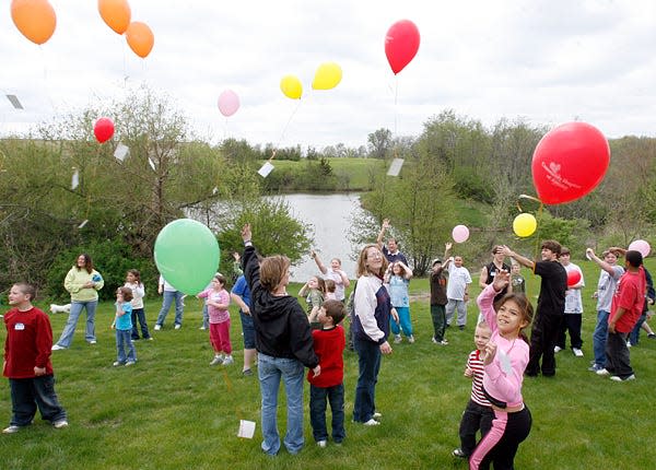 Children release balloons with attached notes, intended for deceased loved ones, at Carl Sandburg College during a previous Children's Grief Camp.