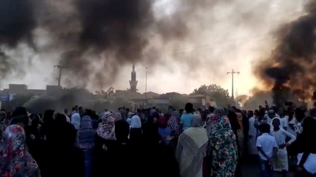 People gather on the streets as smoke rises in Kartoum, Sudan, amid reports of a coup