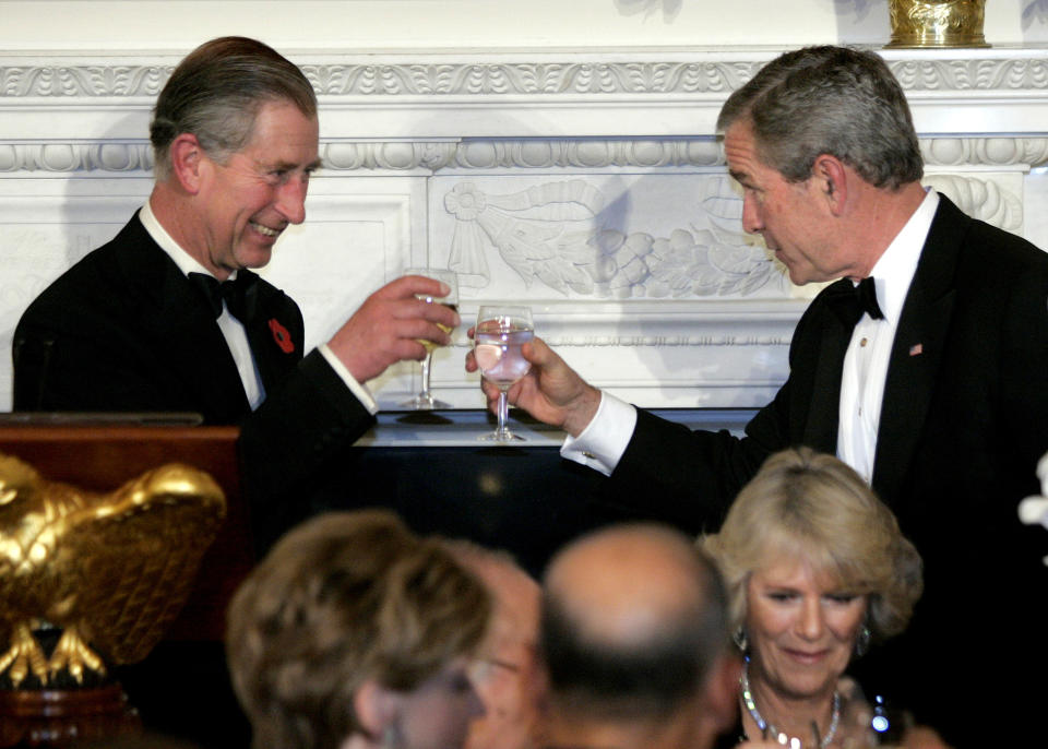 FILE - Britain's Prince Charles makes a toast with President George W. Bush at the start of a Social Dinner in the State Dining Room of the White House, Nov. 2, 2005, in Washington. The dinner is honor of Prince Charles and Camilla, Duchess of Cornwall, seen seated foreground right. (AP Photo/Lawrence Jackson, File)