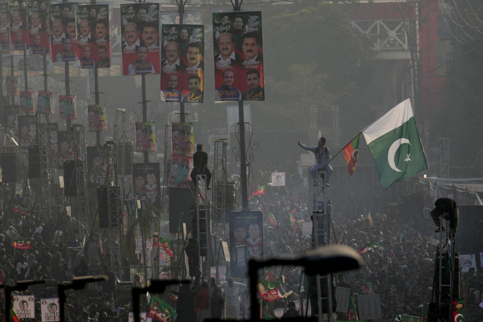 Supporters of Pakistan's former Prime Minister Imran Khan's 'Pakistan Tehreek-e-Insaf' party climb on poles while they participate in a rally, in Rawalpindi, Pakistan, Saturday, Nov. 26, 2022. Khan said Saturday his party was quitting the country's regional and national assemblies, as he made his first public appearance since being wounded in a gun attack earlier this month. (AP Photo/Anjum Naveed)