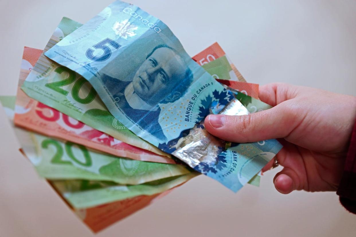 Canadian currency is pictured in Vancouver. According to Canada's Food Price Report 2024, total food prices are expected to increase by 2.5 to 4.5 per cent in 2024.  (Peter Scobie/CBC - image credit)