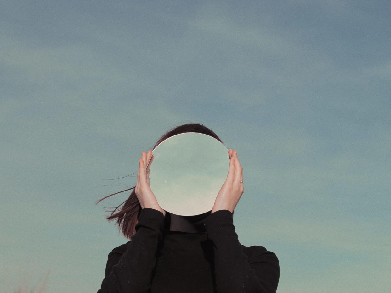 A woman holds a reflective ball in front of her face